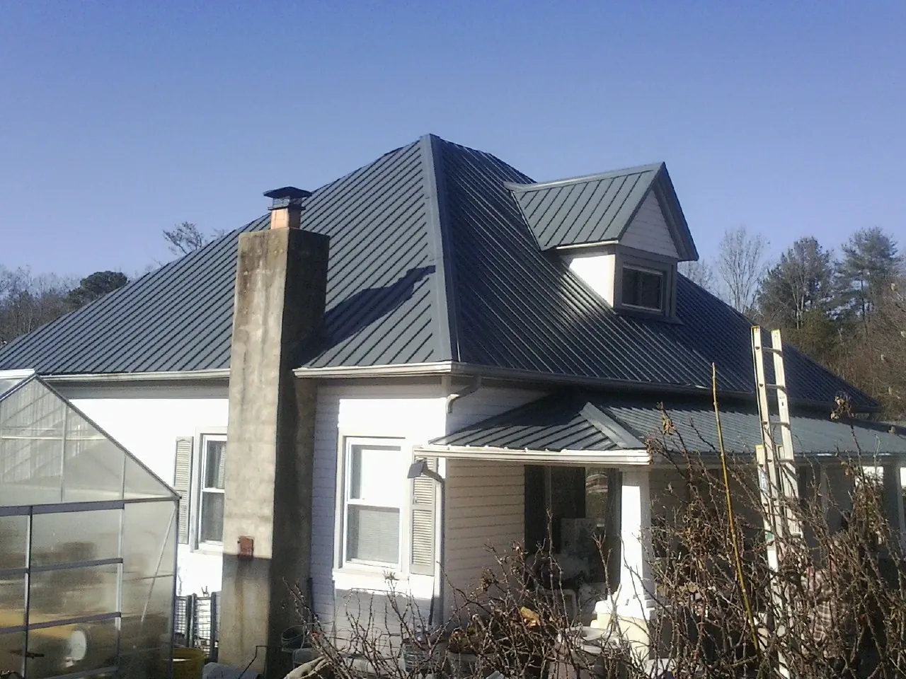Dark blue standing seam metal roof on a white farmhouse with dormer — Slate & Tile Roof Repair by Roofing Brothers in Lorane