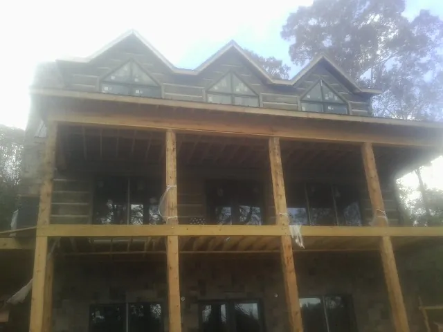 Dormers and porch framing on a large log home under construction — Roof Coating work by our crew in Lorane