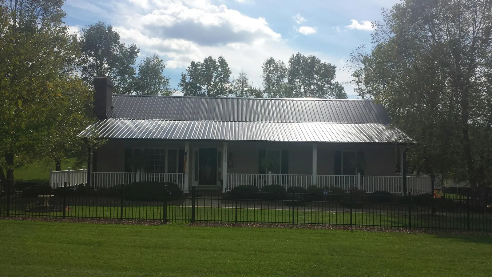 Gray metal roof on a brick ranch with a full width front porch — Gutter Guard Installation work by our crew in Lorane